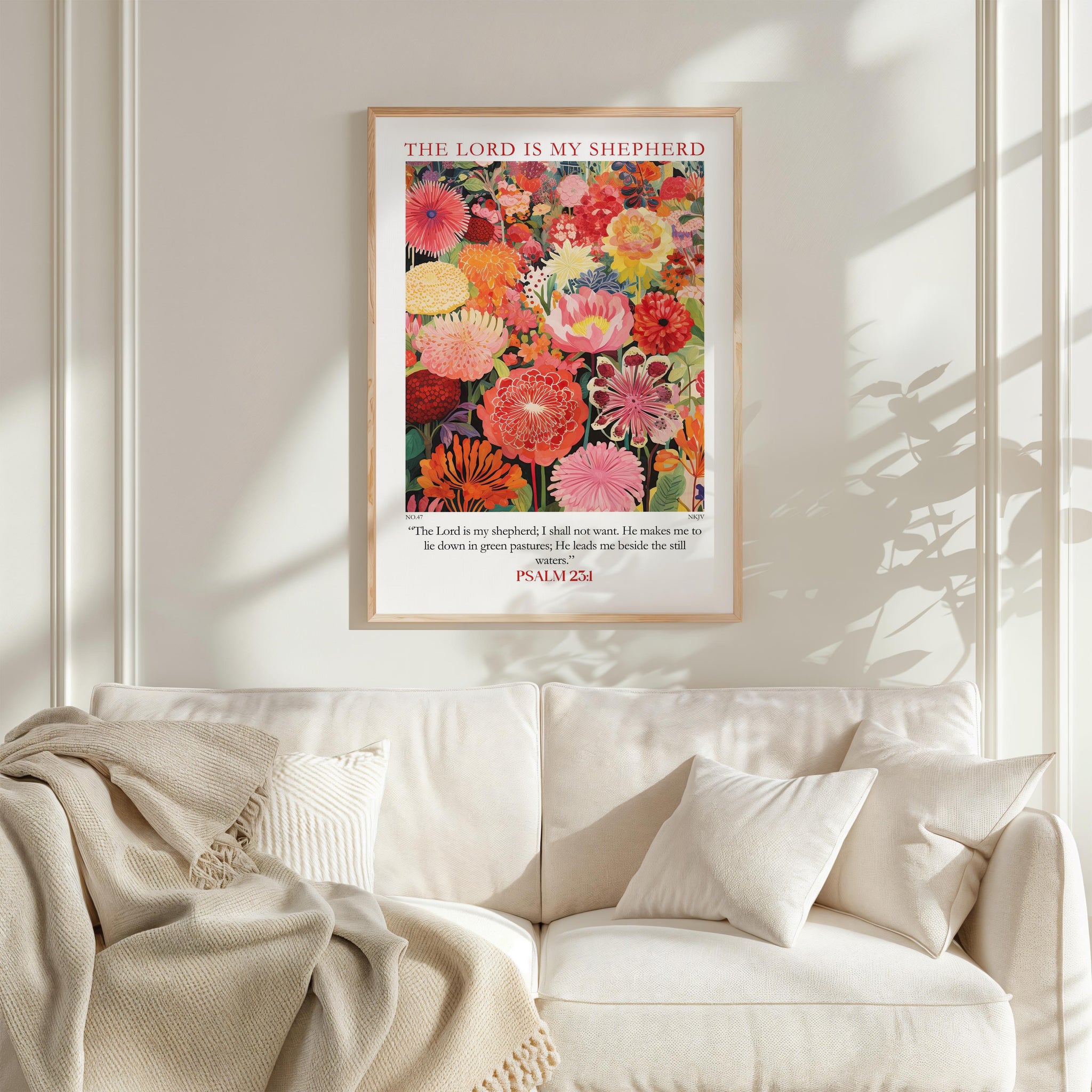 a framed poster of a vibrant floral arrangement hanging on a white wall above a white couch.
