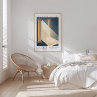 a serene bedroom scene with a bed, a woven chair, and a framed poster on the wall.