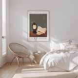 A bedroom with a bed, a woven chair, and a framed poster on the wall.