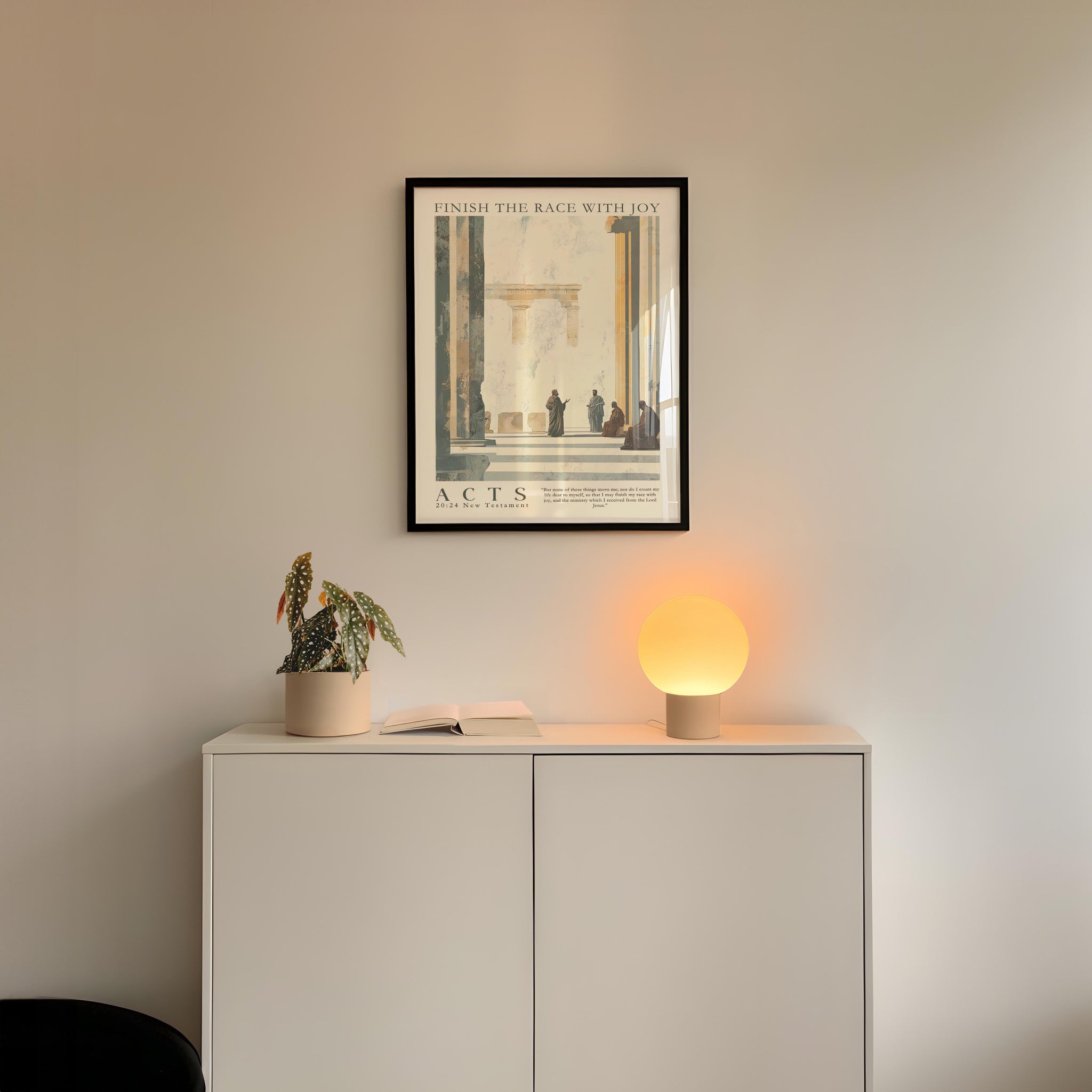 a minimalist interior design with a framed poster of a classical architectural scene hanging on a white wall above a white cabinet. The cabinet has a plant and a lamp on it, creating a cozy and inviting atmosphere.