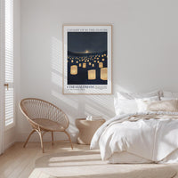 a serene bedroom scene with a bed, a woven chair, and a framed poster of a night sky with floating lanterns.