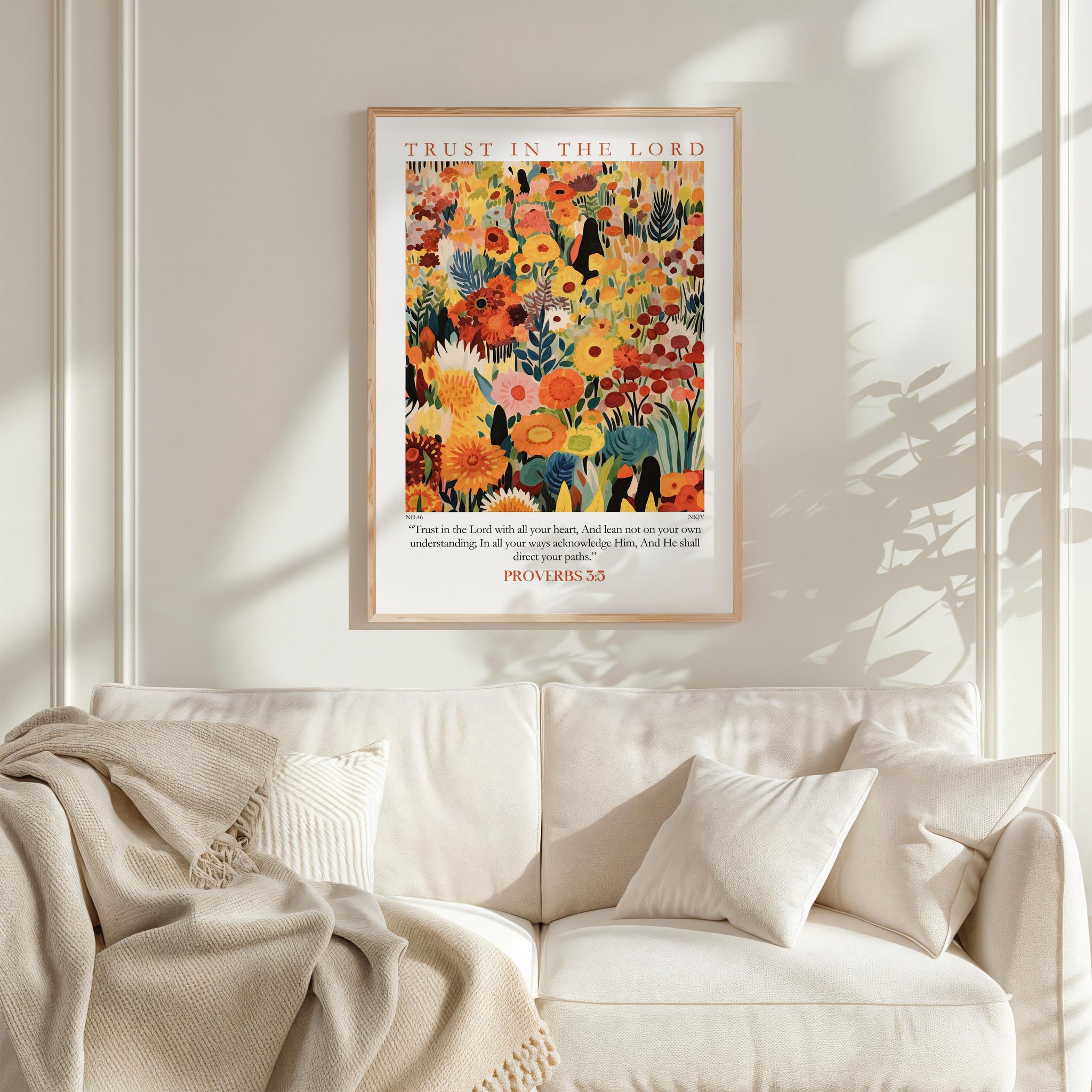 a large, colorful poster of a garden with flowers hanging on a white wall above a white couch with pillows.