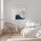 a serene bedroom scene with a bed, a woven chair, and a framed poster of a mountain landscape with a rainbow.