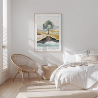 a serene bedroom scene with a bed, a woven chair, and a framed poster of a tree on the wall.