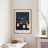 a framed poster of a nighttime scene with numerous lit lanterns, hanging on a wall in a room.