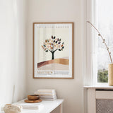 a framed poster of a tree with leaves, hanging on a wall in a room with a white table and a window.