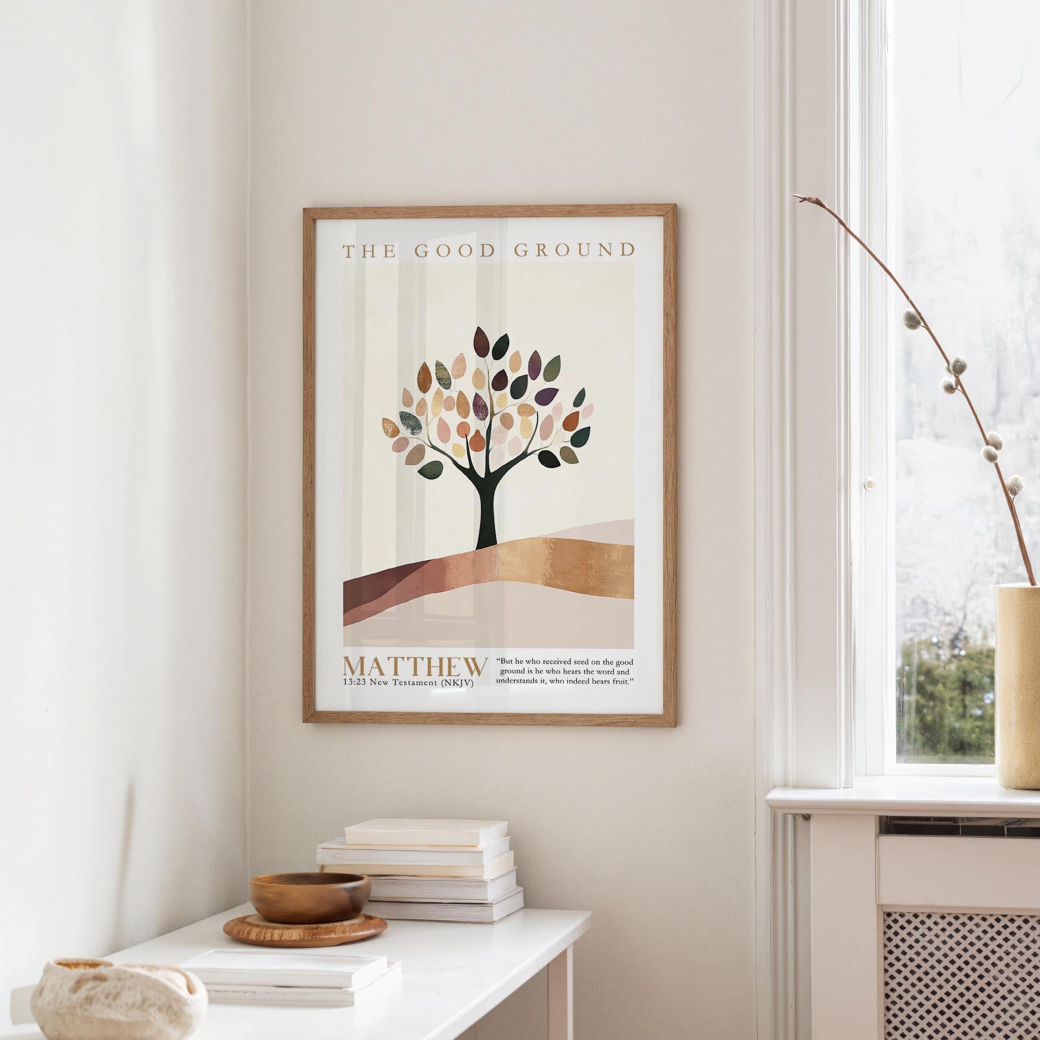 a framed poster of a tree with leaves, hanging on a wall in a room with a white table and a window.