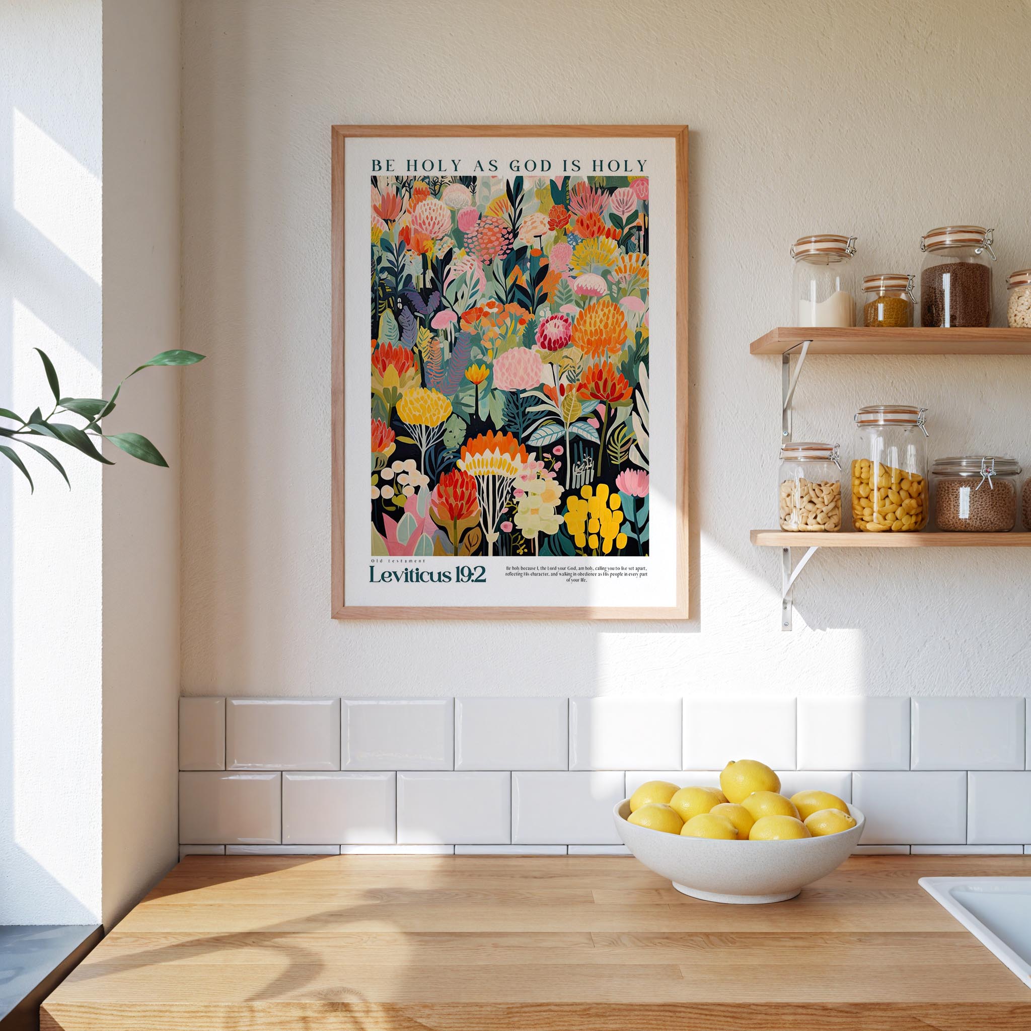 a kitchen scene with a framed poster of a colorful floral design hanging on the wall above a wooden countertop. On the countertop, there is a bowl of lemons and a plant.