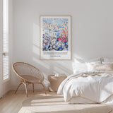 A bedroom with a large bed, a woven chair, and a framed poster of a colorful floral scene on the wall.