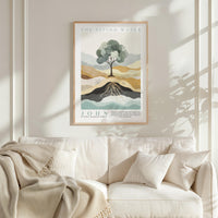 a framed poster of a tree with roots, hanging on a wall above a white couch with a blanket draped over it.