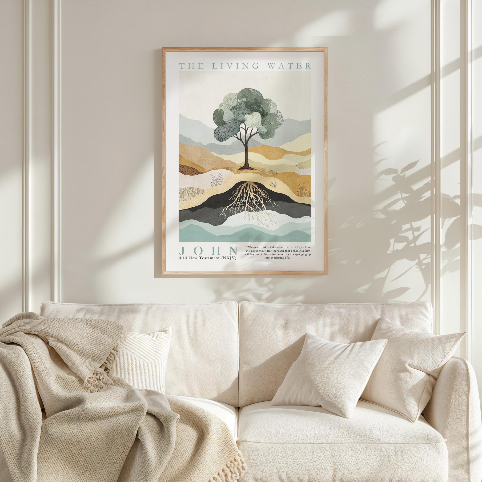 a framed poster of a tree with roots, hanging on a wall above a white couch with a blanket draped over it.