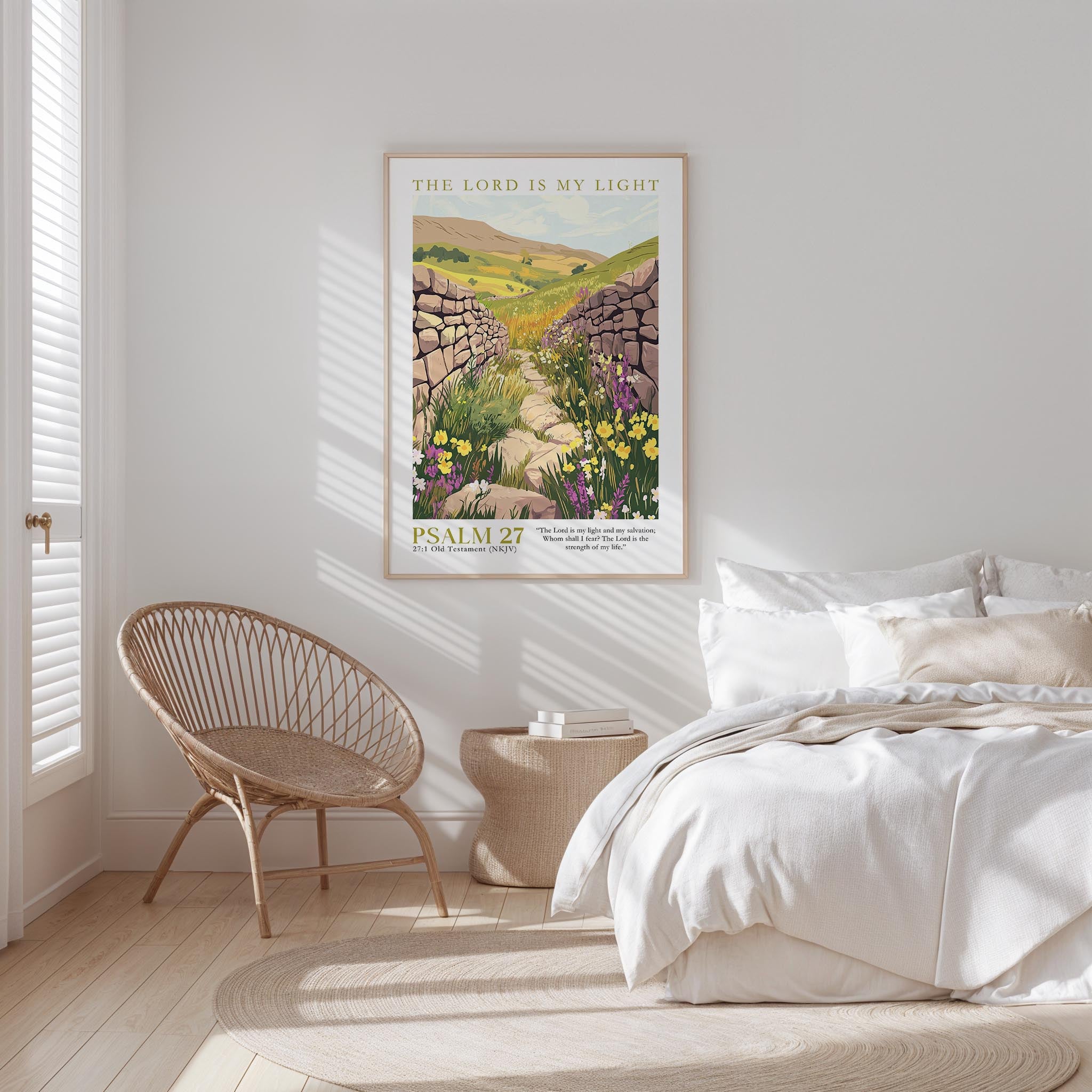 A bedroom with a bed, a woven chair, and a framed poster of a pastoral landscape hanging on the wall.