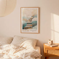 A framed poster of a staircase leading to clouds hangs on a wall above a bed with striped pillows.