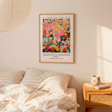 a bedroom setting with a bed, a nightstand, and a framed poster of a colorful floral design hanging on the wall above the bed.