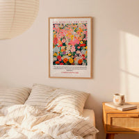 a bedroom setting with a bed, a nightstand, and a framed poster of a colorful floral design hanging on the wall above the bed.
