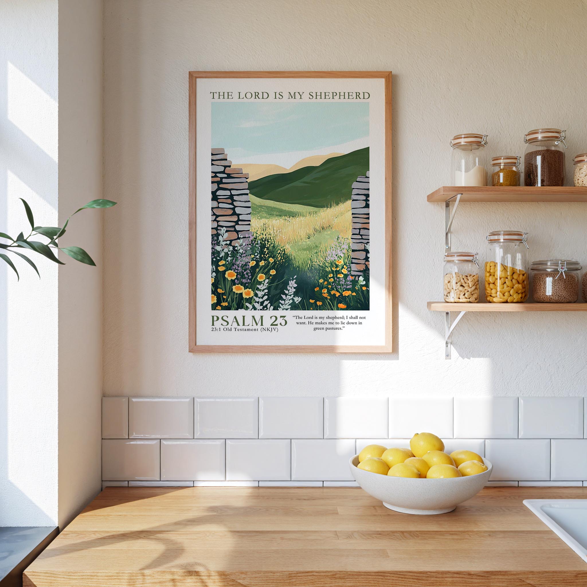 a kitchen scene with a framed poster of a countryside landscape hanging on the wall above a wooden countertop with a bowl of lemons.