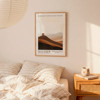 a bedroom setting with a framed poster of a mountain landscape hanging on the wall above a bed with striped bedding.