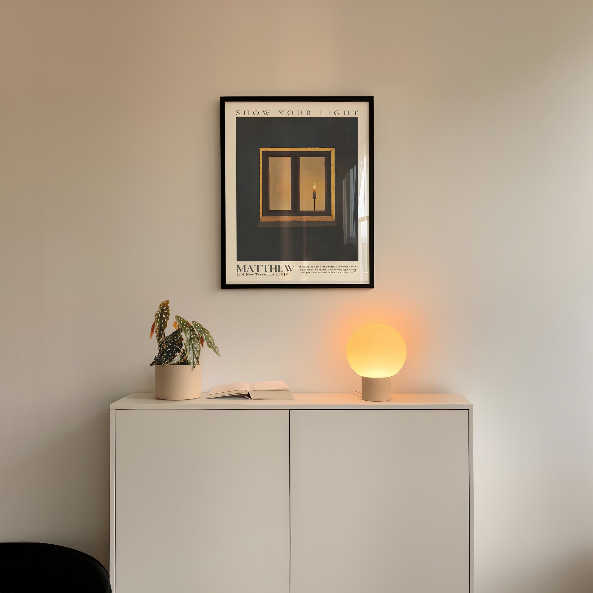 a minimalist interior design with a framed poster of a window, a potted plant, and a small lamp on a white cabinet.