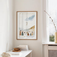 a framed poster of a religious scene hanging on a wall, with a window and a table with books and a bowl on it below.