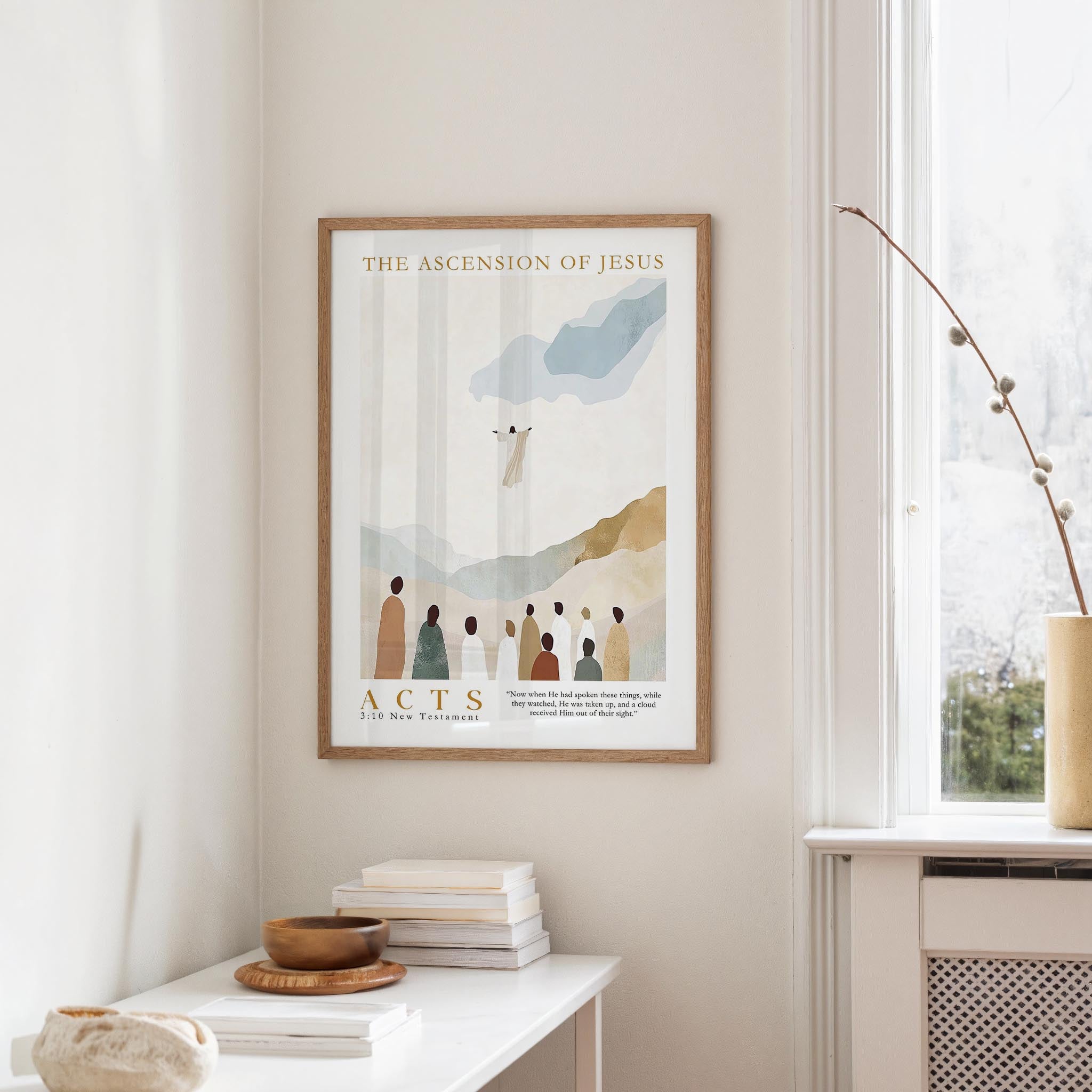 a framed poster of a religious scene hanging on a wall, with a window and a table with books and a bowl on it below.