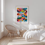 a bedroom with a bed, a woven chair, and a poster of colorful birds on the wall.