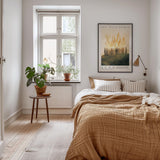 a cozy bedroom with a large bed, a nightstand, and a framed poster on the wall. The room has a warm, inviting atmosphere with a wooden floor and a rug.