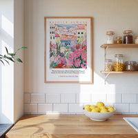 a kitchen scene with a framed poster of a colorful garden hanging on the wall above a wooden countertop with a bowl of lemons.
