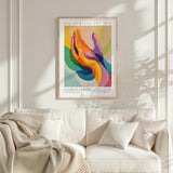a vibrant abstract painting hanging on a white wall above a white couch with a blanket draped over it.