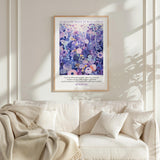 a framed poster of a vibrant floral scene hanging on a white wall above a white couch with a blanket draped over it.