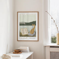 a framed poster of Psalm 19 hanging on a wall, with a window and a small table with books and a vase nearby.