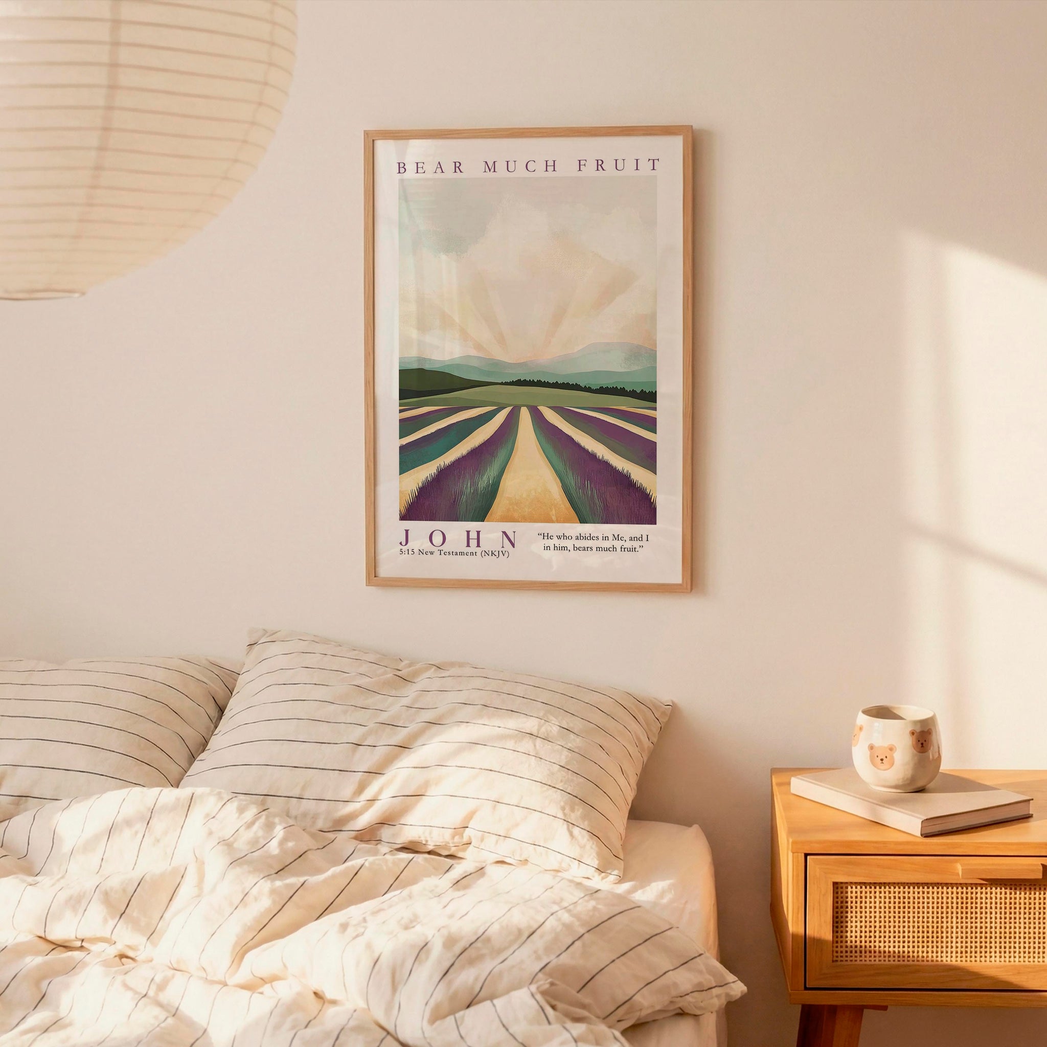 a bedroom setting with a framed poster of a countryside landscape hanging on the wall above a bed with striped bedding.