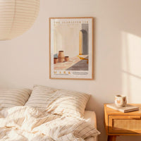 a bedroom setting with a framed poster of a desert scene hanging on the wall above a bed with striped bedding.