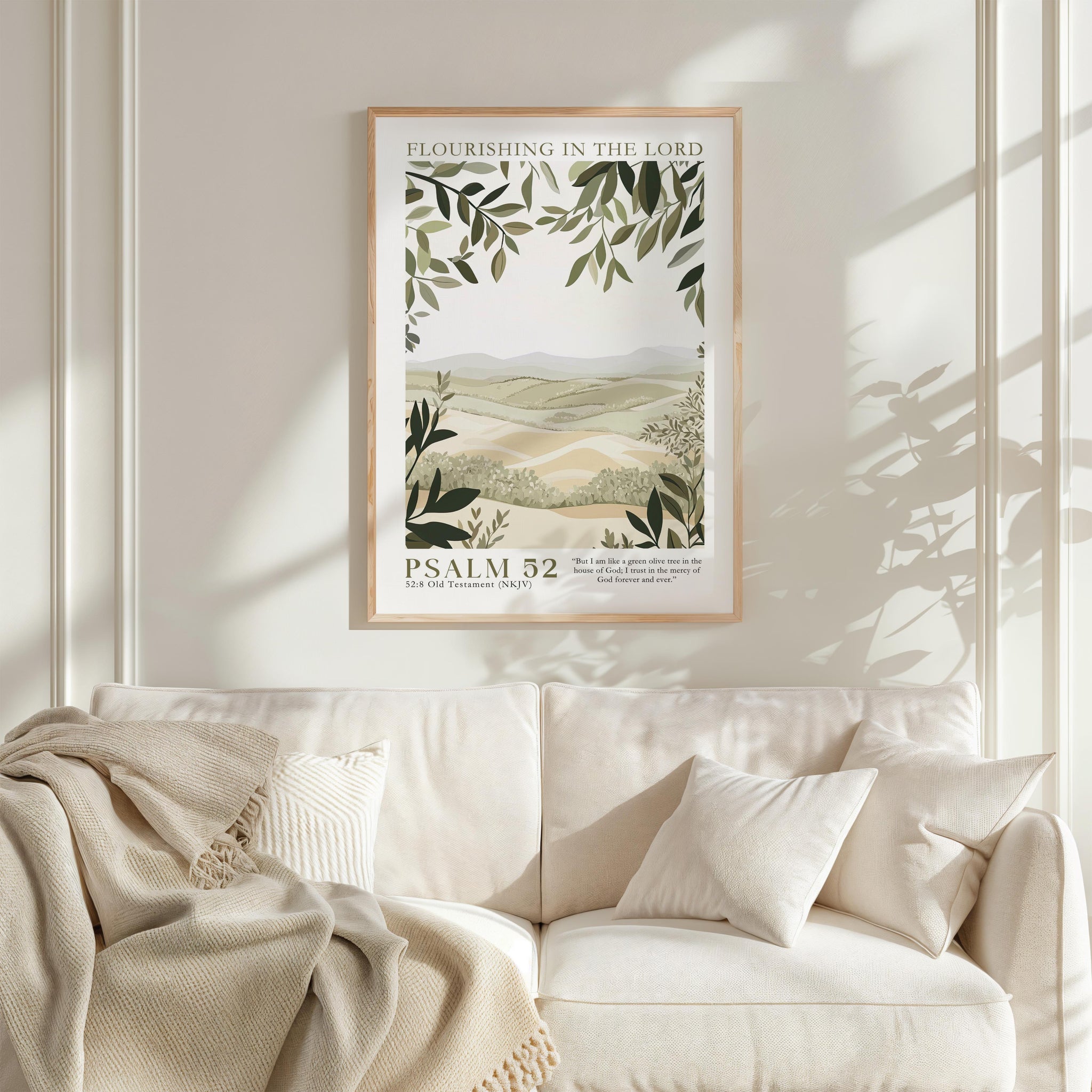 a framed poster of a landscape with greenery hanging on a wall above a white couch with pillows.