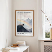 a framed poster of a mountain landscape with a rainbow, hanging on a wall in a room with a white table and a vase of flowers.