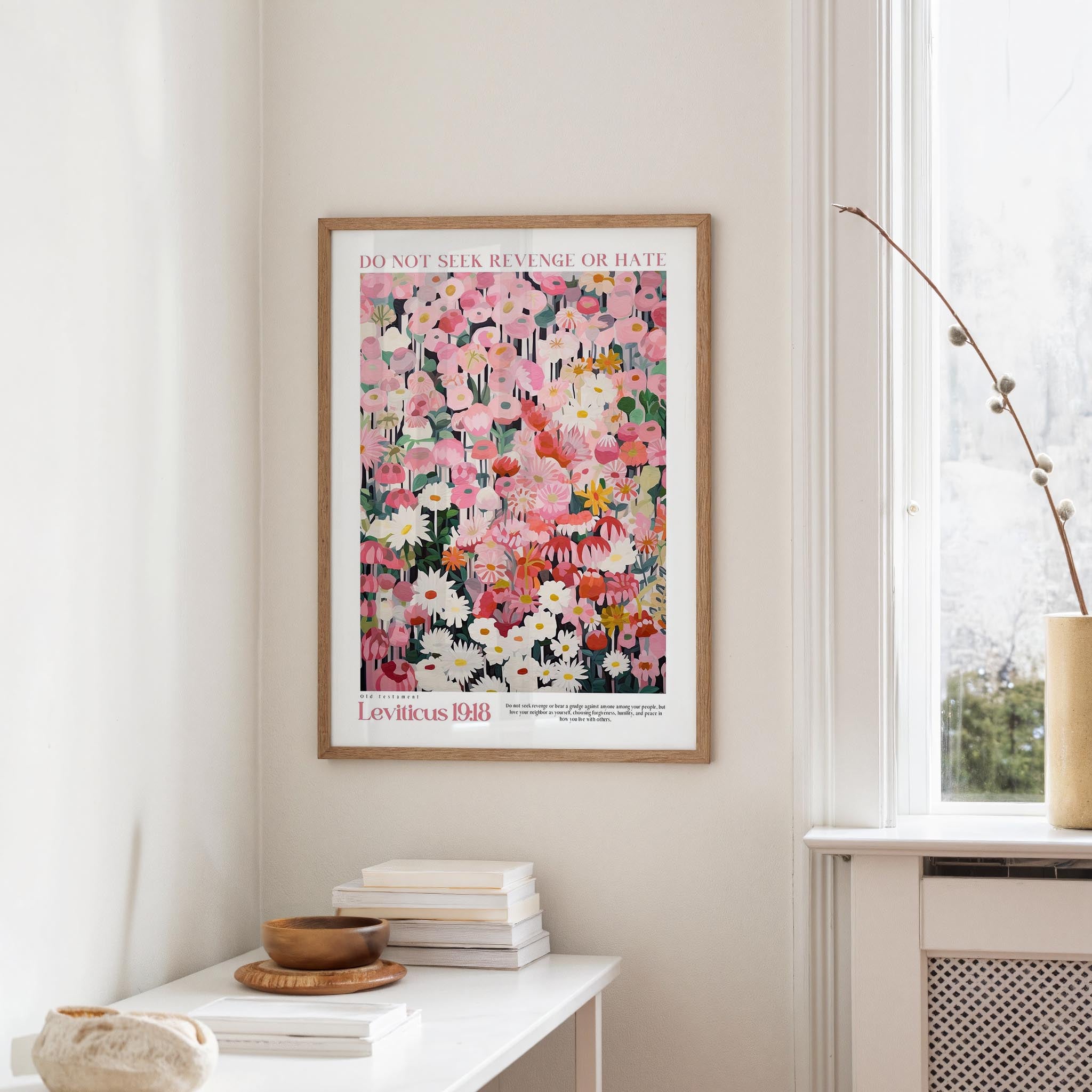 a framed poster of a colorful floral arrangement hanging on a wall, with a white table and a vase of flowers nearby.