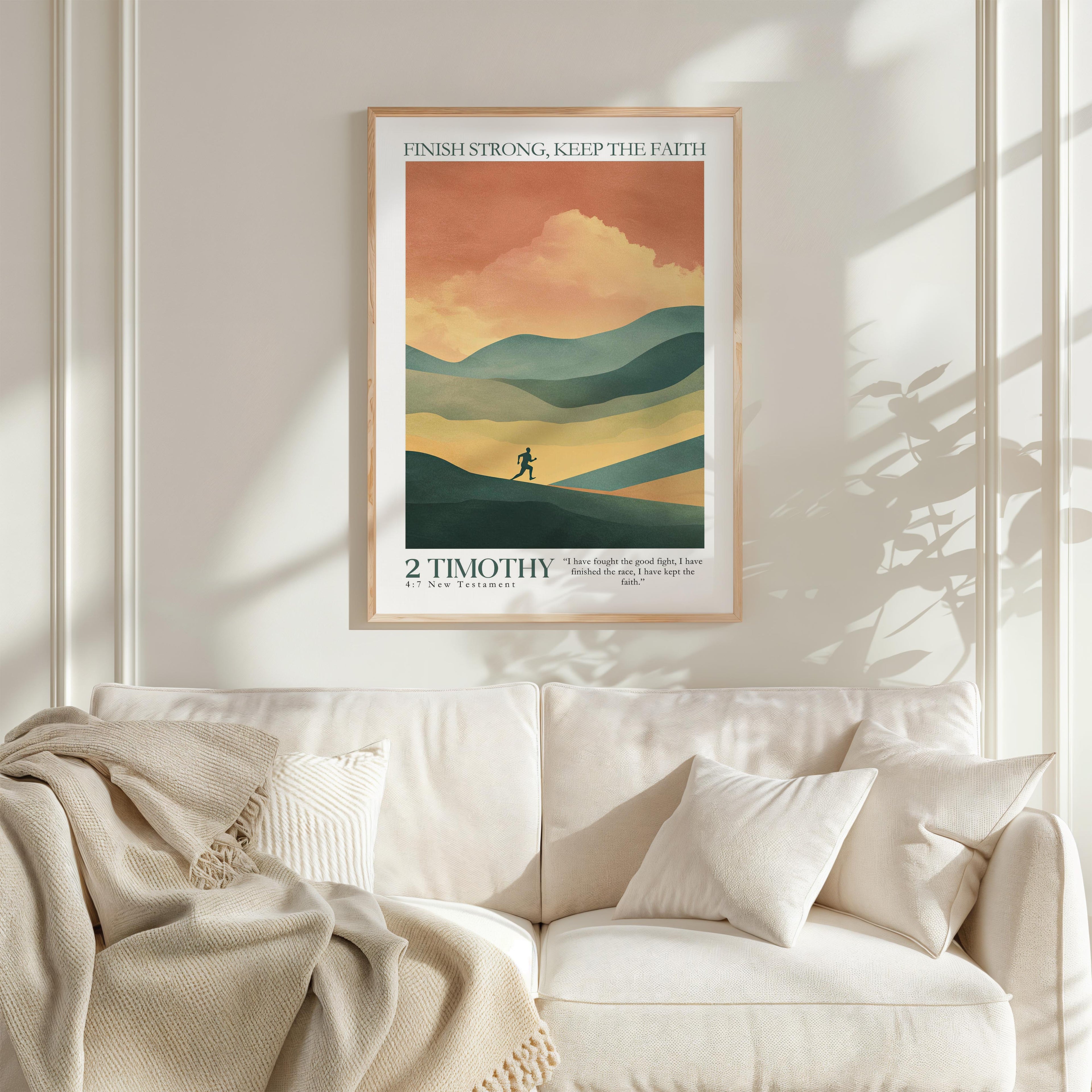 a framed poster of a mountain landscape with a person walking on a trail, hanging on a wall above a white couch with a blanket draped over it.