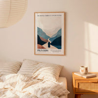 a bedroom setting with a framed poster of a mountain landscape hanging on the wall above a bed with striped bedding.