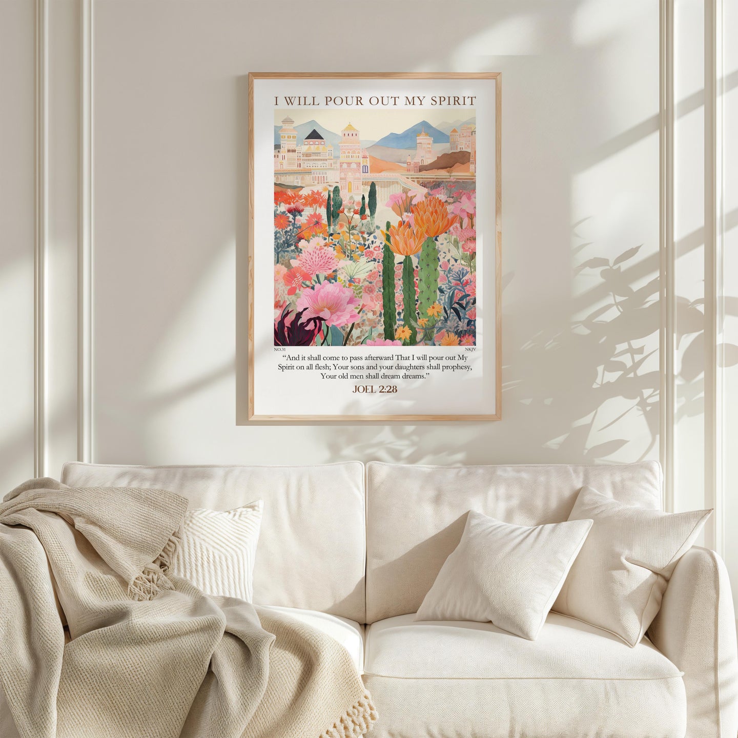 a framed poster of a colorful garden scene hanging on a wall above a white couch.
