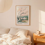 a bedroom scene with a framed poster of a floral design hanging on the wall above a bed with striped pillows.