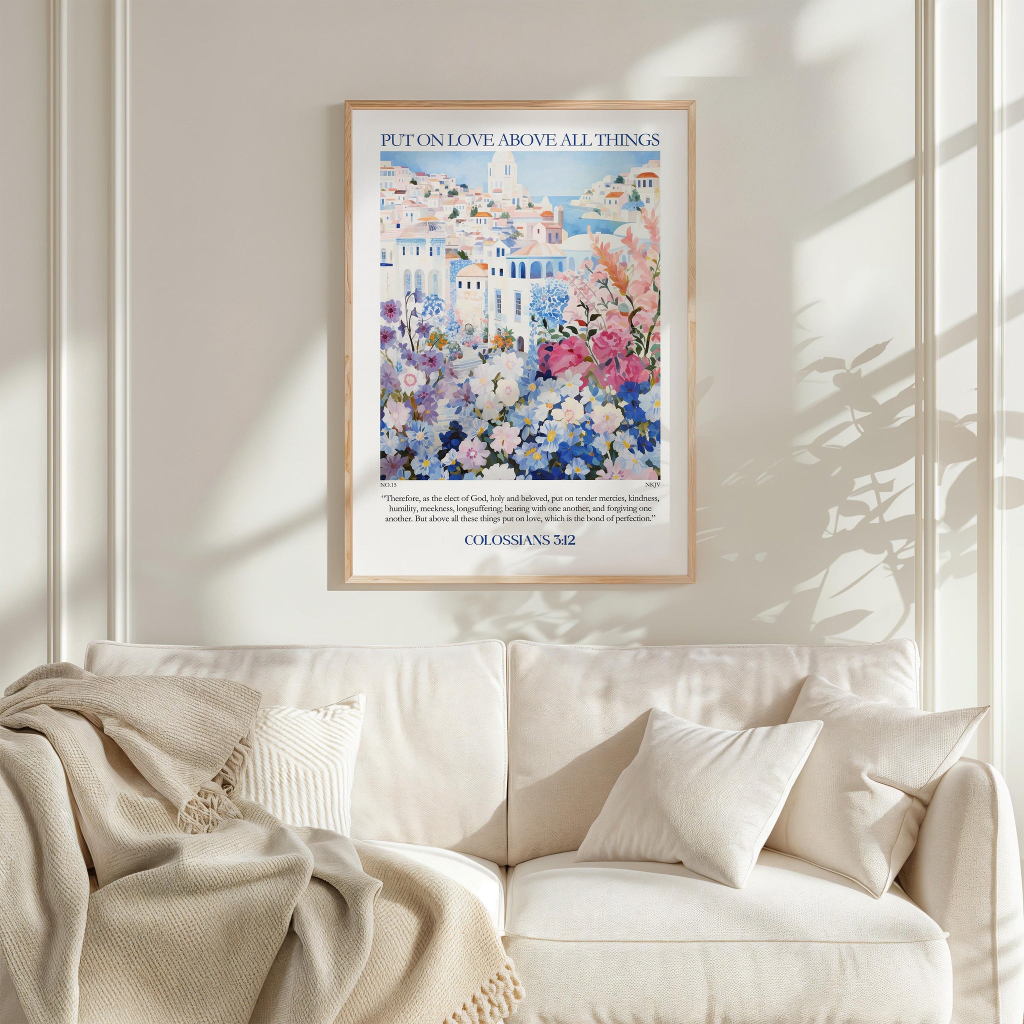 a framed poster of a colorful floral scene hanging on a wall above a white couch with pillows.