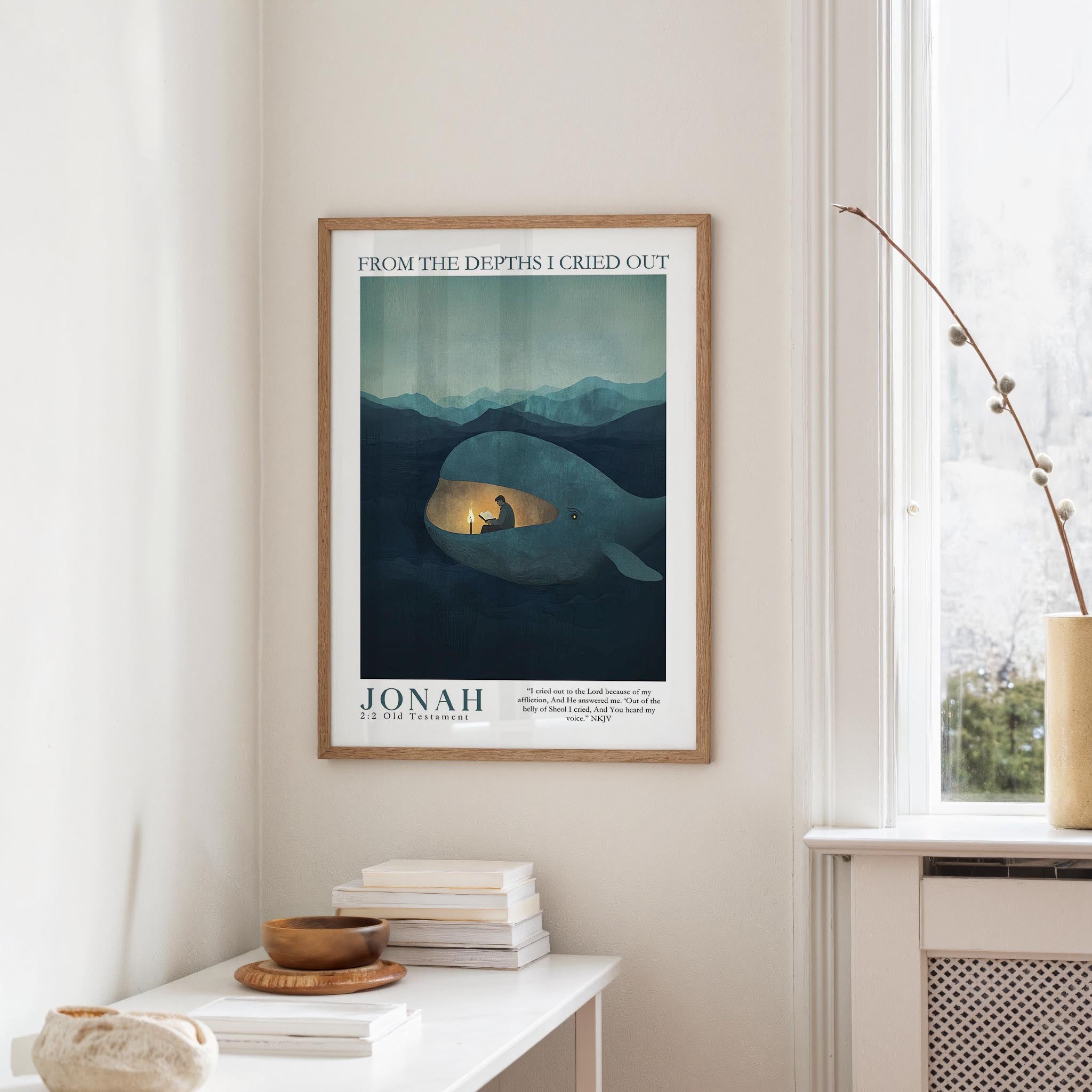 a framed poster of a whale with a person inside, hanging on a wall in a room with a window and a table with books and a bowl on it.