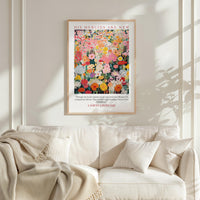 a poster of a colorful floral arrangement hanging on a wall above a white couch.