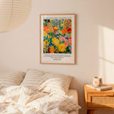 a bedroom setting with a bed, a nightstand, and a framed poster of a colorful floral design hanging on the wall above the bed.
