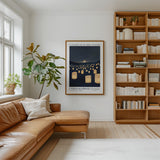 a cozy living room with a large bookshelf filled with books, a comfortable leather couch, and a framed poster of a lantern-filled sky hanging on the wall.