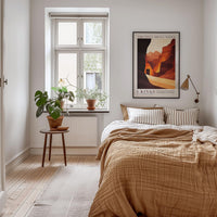 a cozy bedroom with a large bed, a wooden nightstand, and a framed poster on the wall. The room has a warm, inviting atmosphere with a wooden floor and a rug.