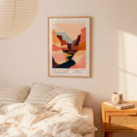 a bedroom setting with a framed poster of a mountain landscape hanging on the wall above a bed with striped bedding.