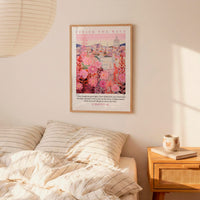 a bedroom setting with a framed poster of a cityscape hanging on the wall above a bed with striped bedding.