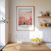 a kitchen scene with a framed poster of a colorful garden hanging on the wall above a wooden countertop with a bowl of lemons.