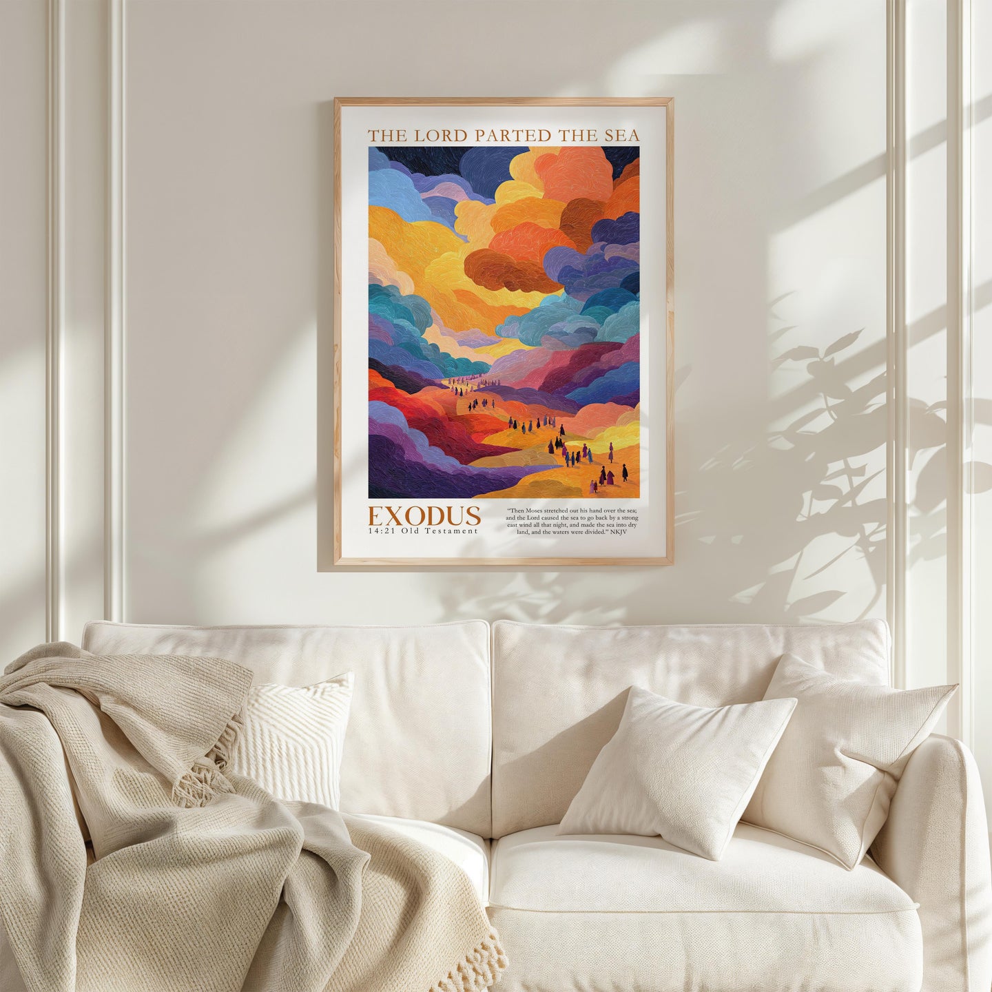 a vibrant poster of a landscape with a colorful sky and clouds, hanging on a wall above a white couch with a blanket draped over it.