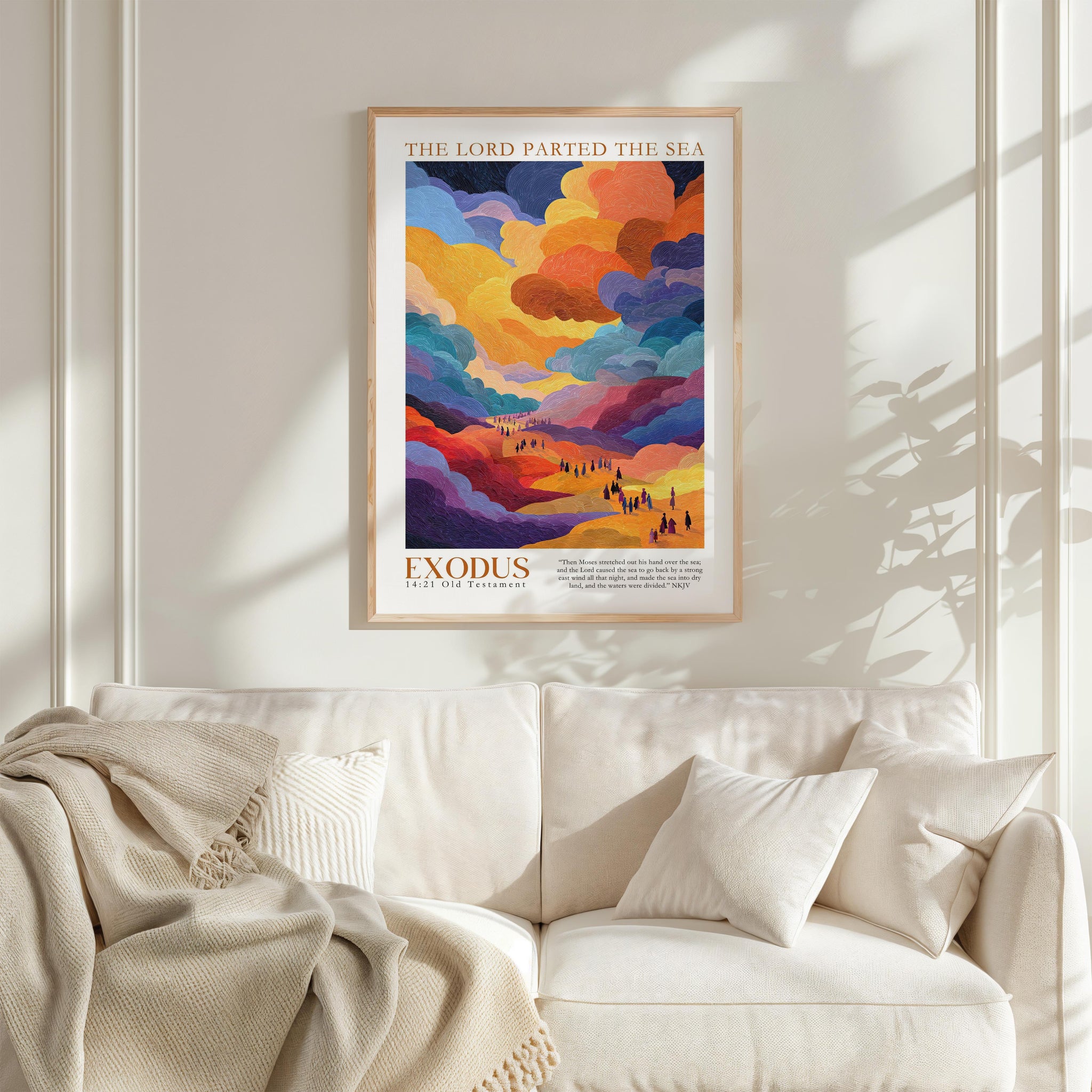 a vibrant poster of a landscape with a colorful sky and clouds, hanging on a wall above a white couch with a blanket draped over it.